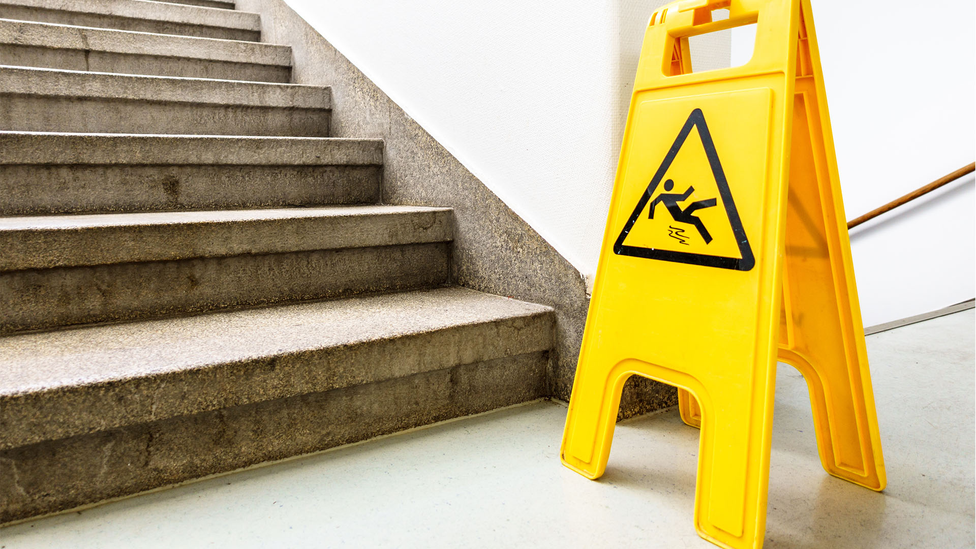 warning sign depicting a falling person placed at the bottom of staircase
